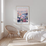 a bedroom with a bed, a woven chair, and a framed poster of a flower market in Adelaide, Australia.