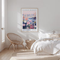 a bedroom with a bed, a woven chair, and a framed poster of a flower market in Adelaide, Australia.