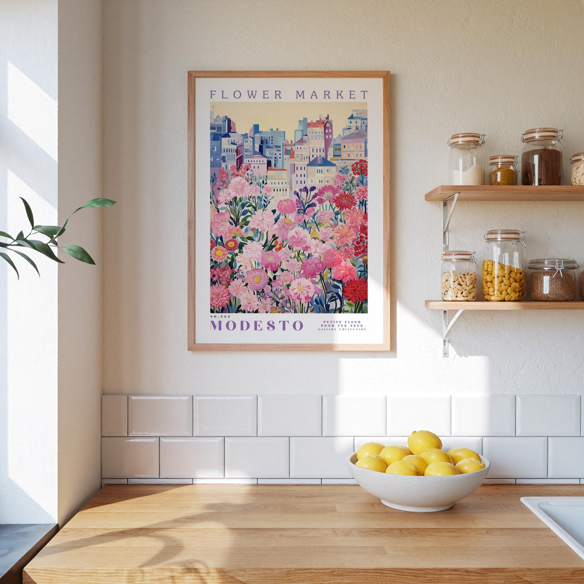 a kitchen counter with a bowl of lemons, a framed poster of a flower market, and shelves with jars and containers.