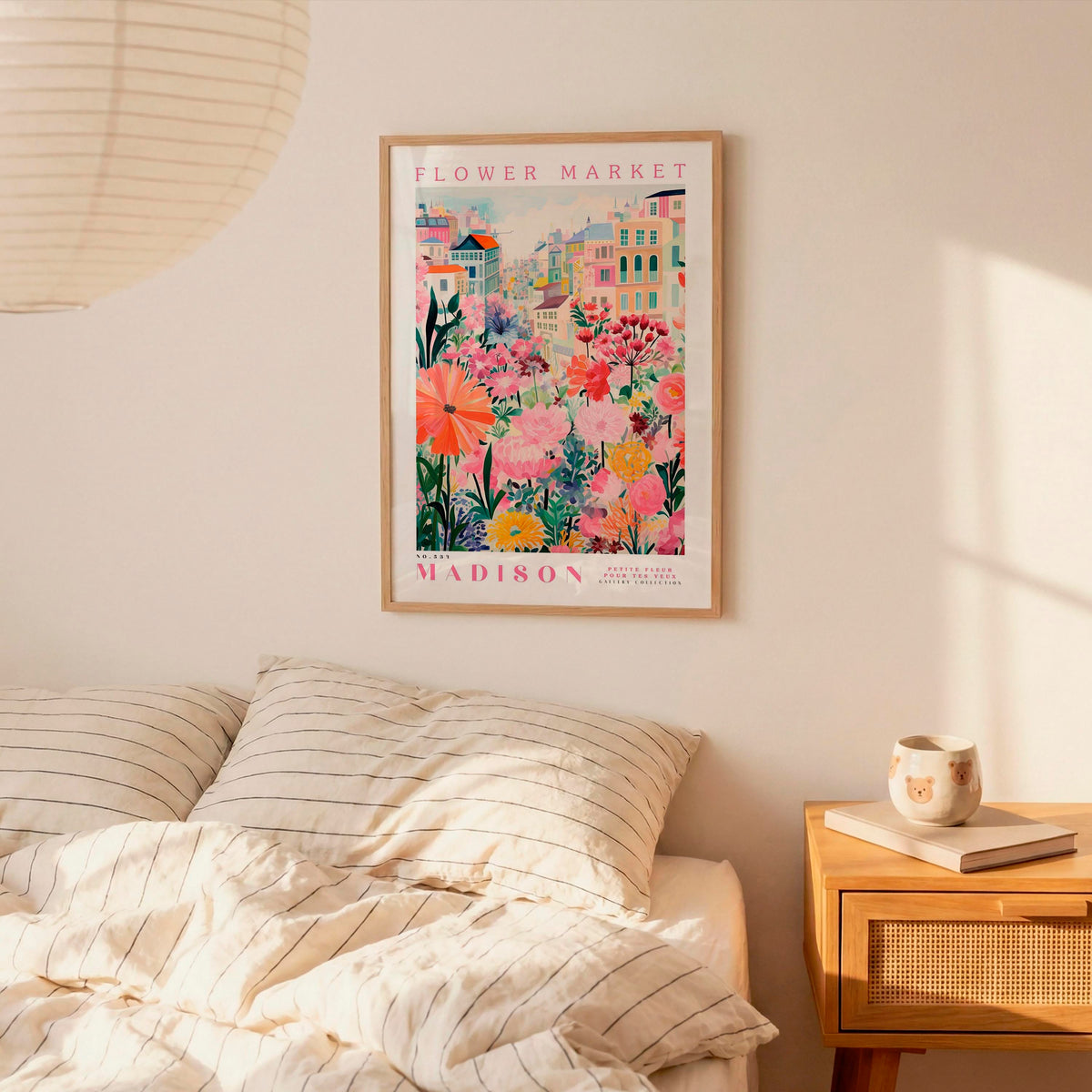 a bedroom scene with a framed poster of a colorful floral scene hanging on the wall above a bed with striped pillows.