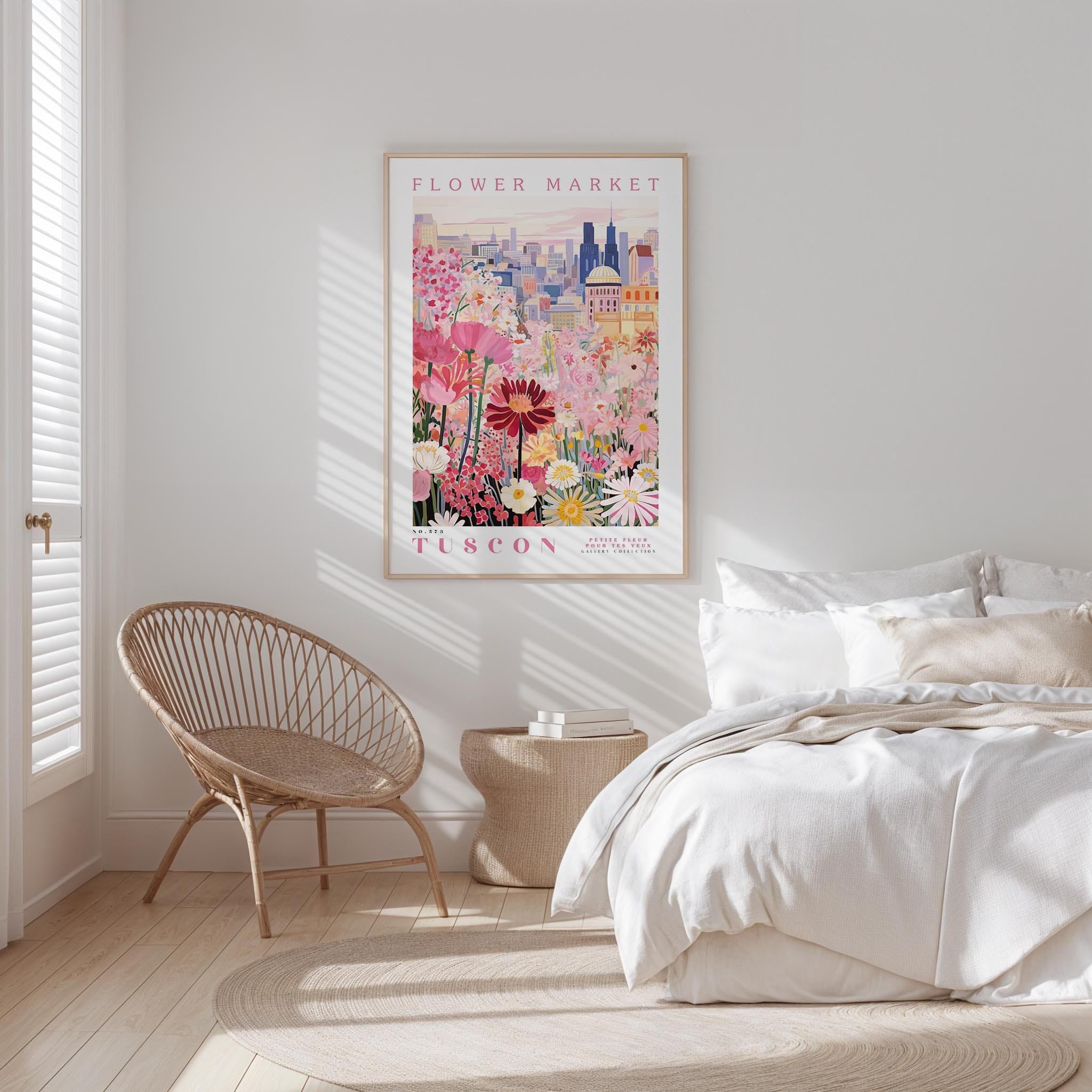 a bedroom with a bed, a woven chair, and a framed poster of a colorful floral scene hanging on the wall.