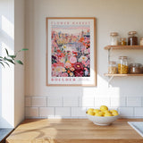 a kitchen scene with a framed poster of a colorful floral scene hanging on the wall above a wooden countertop with a bowl of lemons.