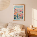 a bedroom scene with a framed poster of a flower market in San Antonio hanging on the wall above a bed with striped pillows.