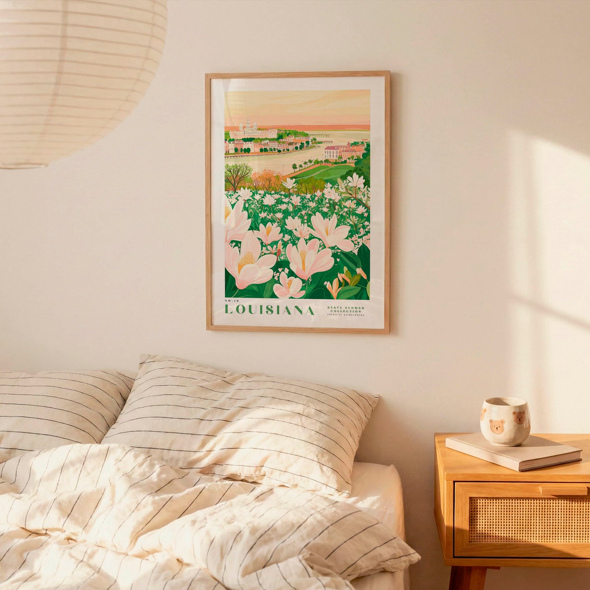 a framed poster of a floral landscape hanging on a wall above a bed with striped pillows.