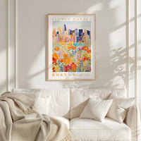 a framed poster of a cityscape with a flower market in the background, hanging on a wall above a white couch with a blanket draped over it.