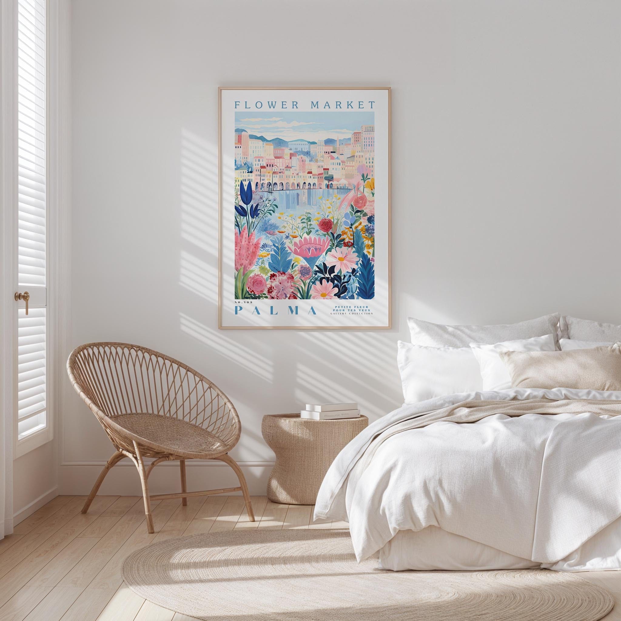 a bedroom with a bed, a woven chair, and a framed poster of a colorful floral scene hanging on the wall.