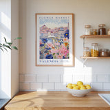 a framed poster of a colorful floral scene hanging on a wall above a wooden countertop with a bowl of lemons.