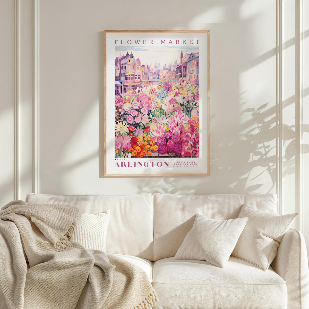 a framed poster of a colorful flower market in Arlington, with a white sofa and a blanket in the foreground.