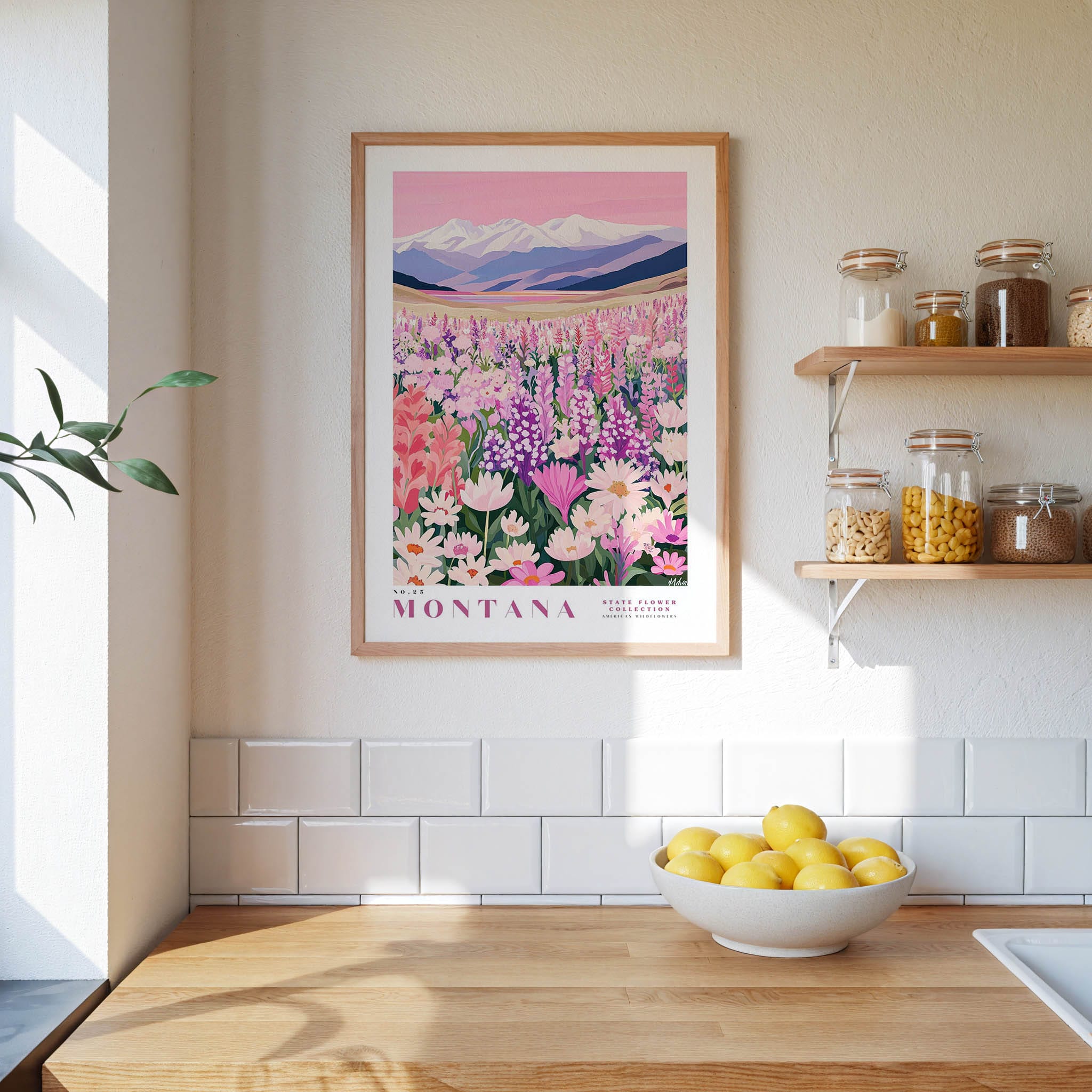 a framed poster of a field of flowers, with the word "Montana" written on it, hanging on a wall above a wooden counter with a bowl of lemons on it.