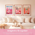 a cozy living room with three framed prints of flower market scenes hanging on the wall. The prints depict Paris, Rome, and Kyoto, creating a harmonious and visually appealing display. The room is furnished with a white sofa and a wooden coffee table, contributing to the overall warm and inviting atmosphere. The text in the image suggests that the prints are designed to fit together, creating a balanced and cohesive look that complements the space.