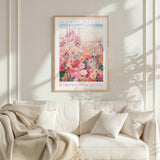 a poster of the Barcelona Flower Market hanging on a wall above a white couch with a blanket draped over it.