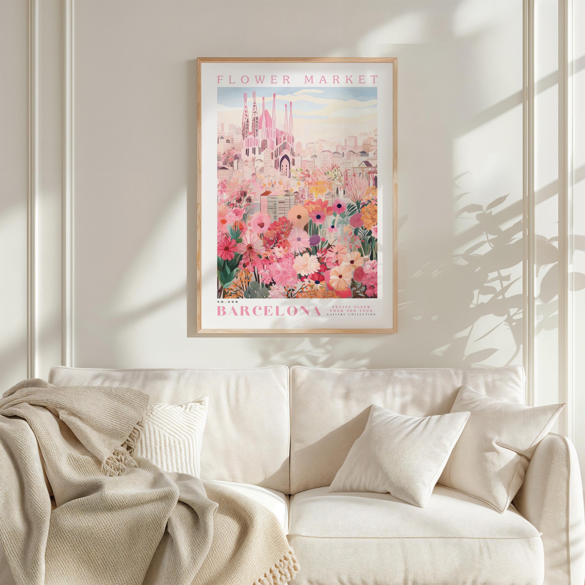 a poster of the Barcelona Flower Market hanging on a wall above a white couch with a blanket draped over it.