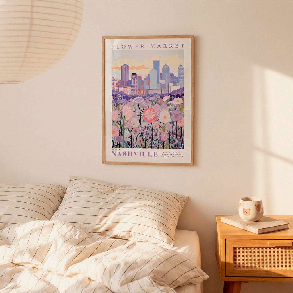 a bedroom setting with a framed poster of a cityscape and flowers hanging on the wall above a bed with striped pillows.