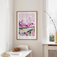a framed poster of a scenic mountain landscape, hanging on a wall in a room with a white table and a window.