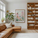 a cozy living room with a large window, a comfortable leather sofa, a wooden bookshelf filled with books, and a framed poster of a flower market in Miami hanging on the wall.