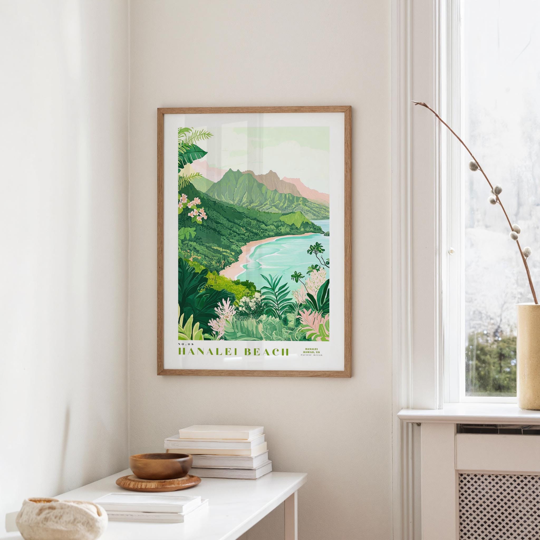 a framed poster of a tropical beach landscape, hanging on a wall in a room with a white table and a vase of flowers.