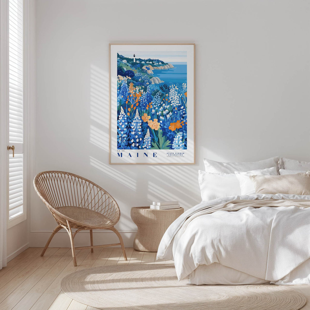 a serene bedroom scene with a large framed poster of a coastal landscape hanging on the wall, a wicker chair, and a bed with white bedding.