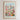 The image is a framed poster depicting a vibrant cityscape with a colorful flower garden in the foreground.