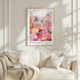 A framed poster of a vibrant floral scene hangs on a wall above a white couch, creating a cozy and inviting atmosphere.