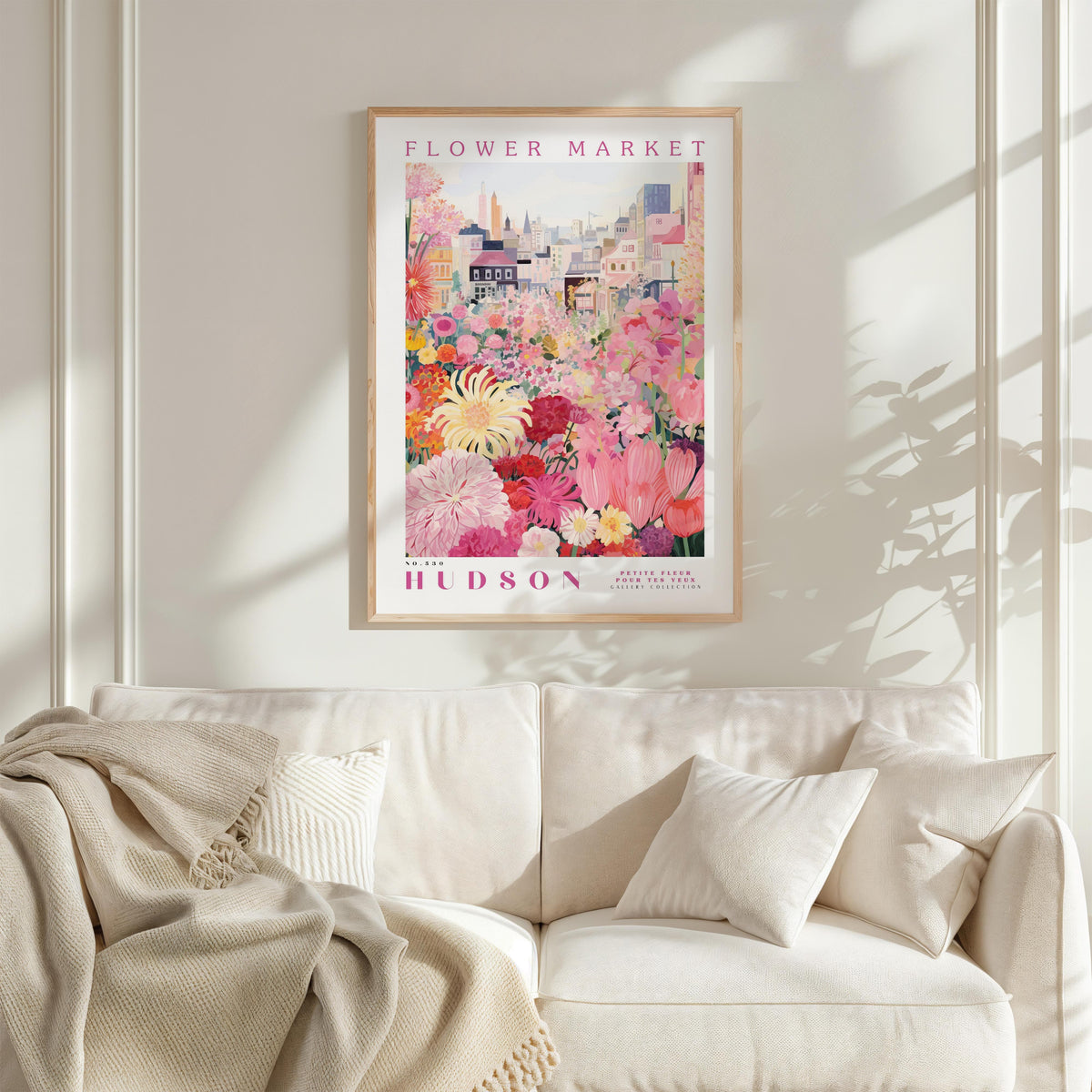 A framed poster of a vibrant floral scene hangs on a wall above a white couch, creating a cozy and inviting atmosphere.