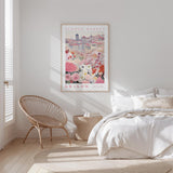 a bedroom with a bed, a woven chair, and a framed poster of a cityscape with flowers hanging on the wall.