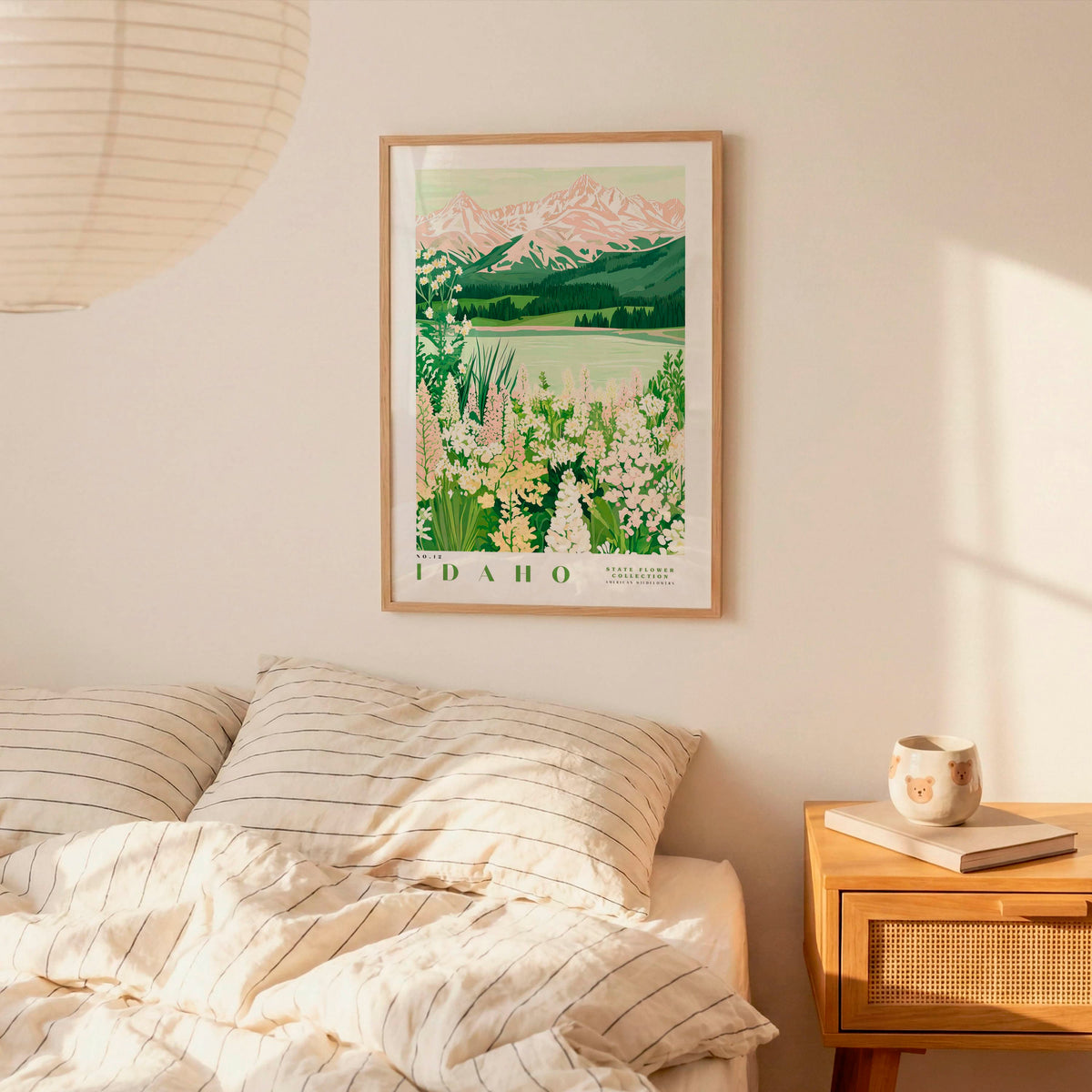 a bedroom with a framed poster of a mountain landscape hanging on the wall above a bed with striped bedding.