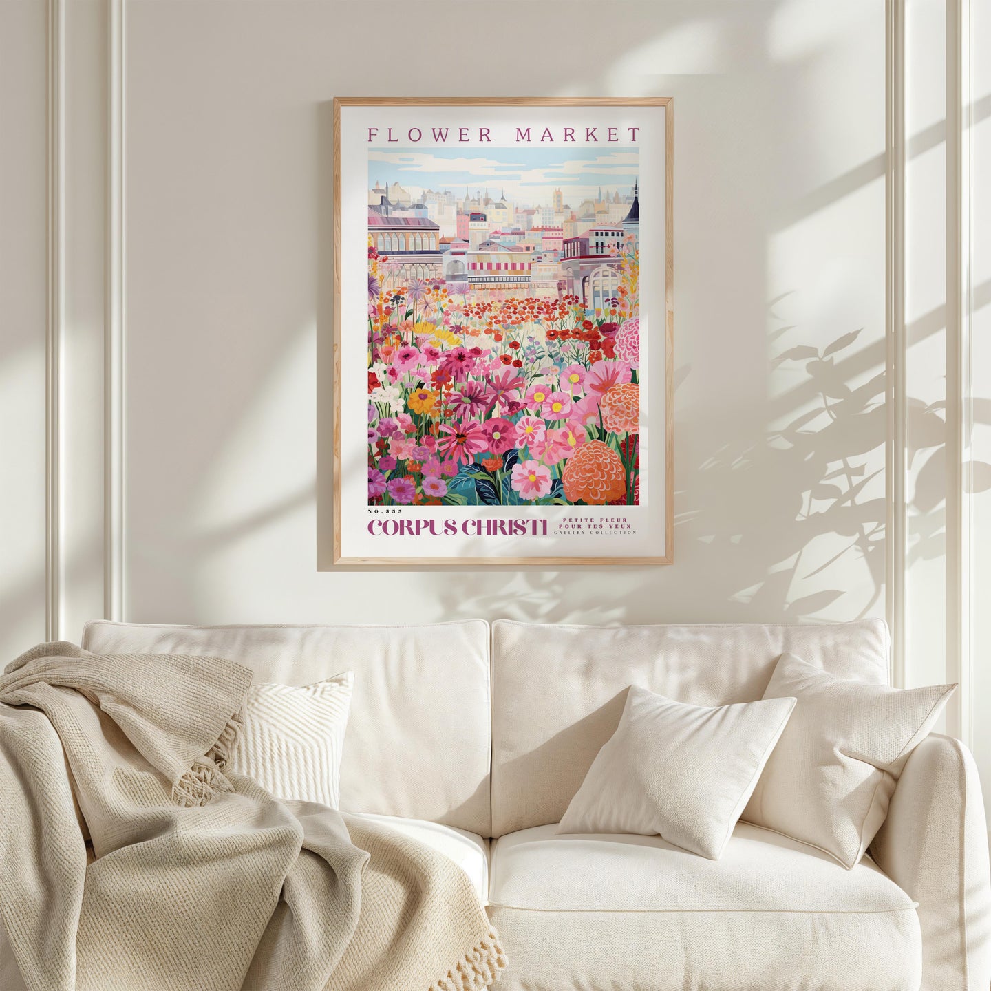 a framed poster of a colorful floral scene hanging on a wall above a white couch.