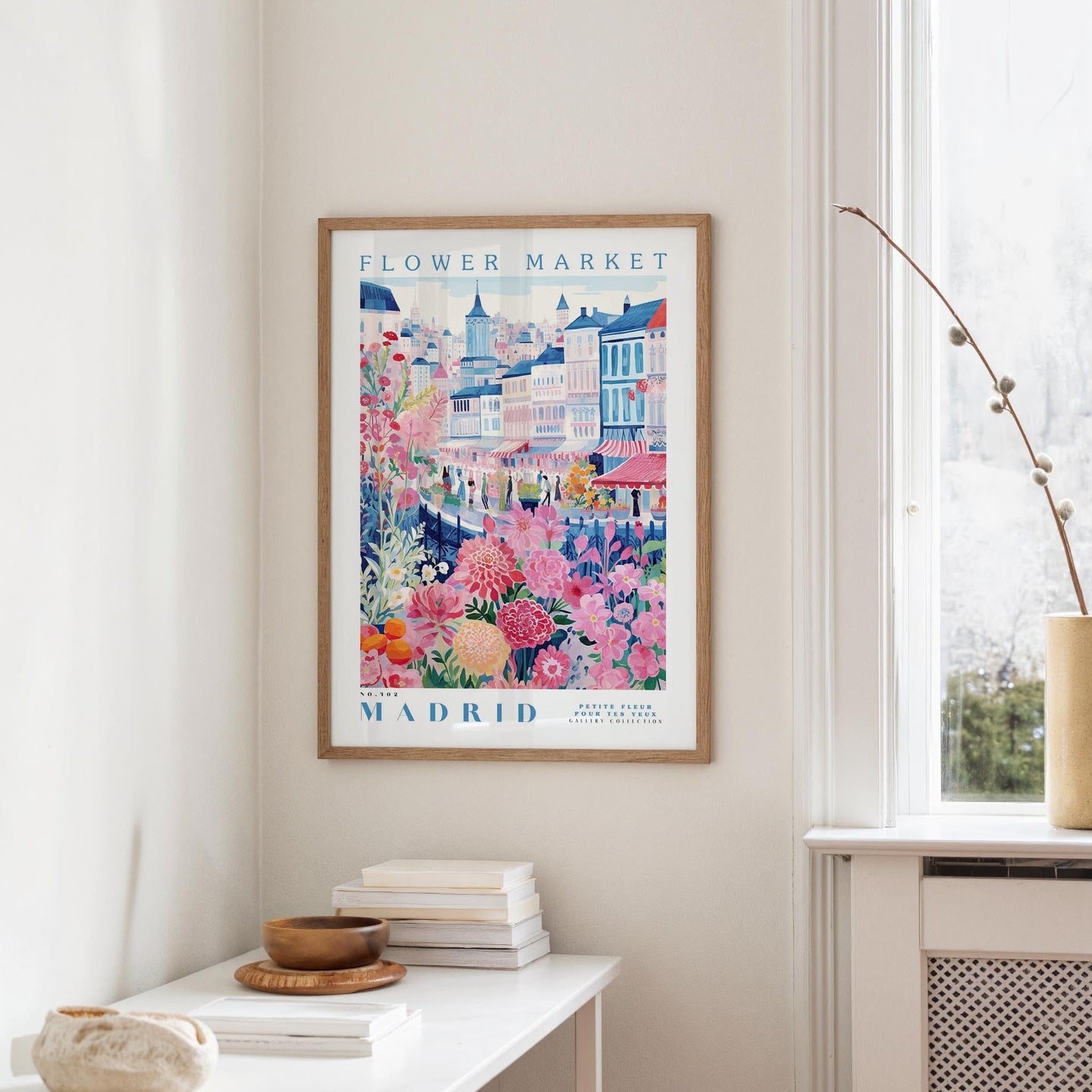 a framed poster of a colorful street scene in Madrid, Spain, hanging on a wall.
