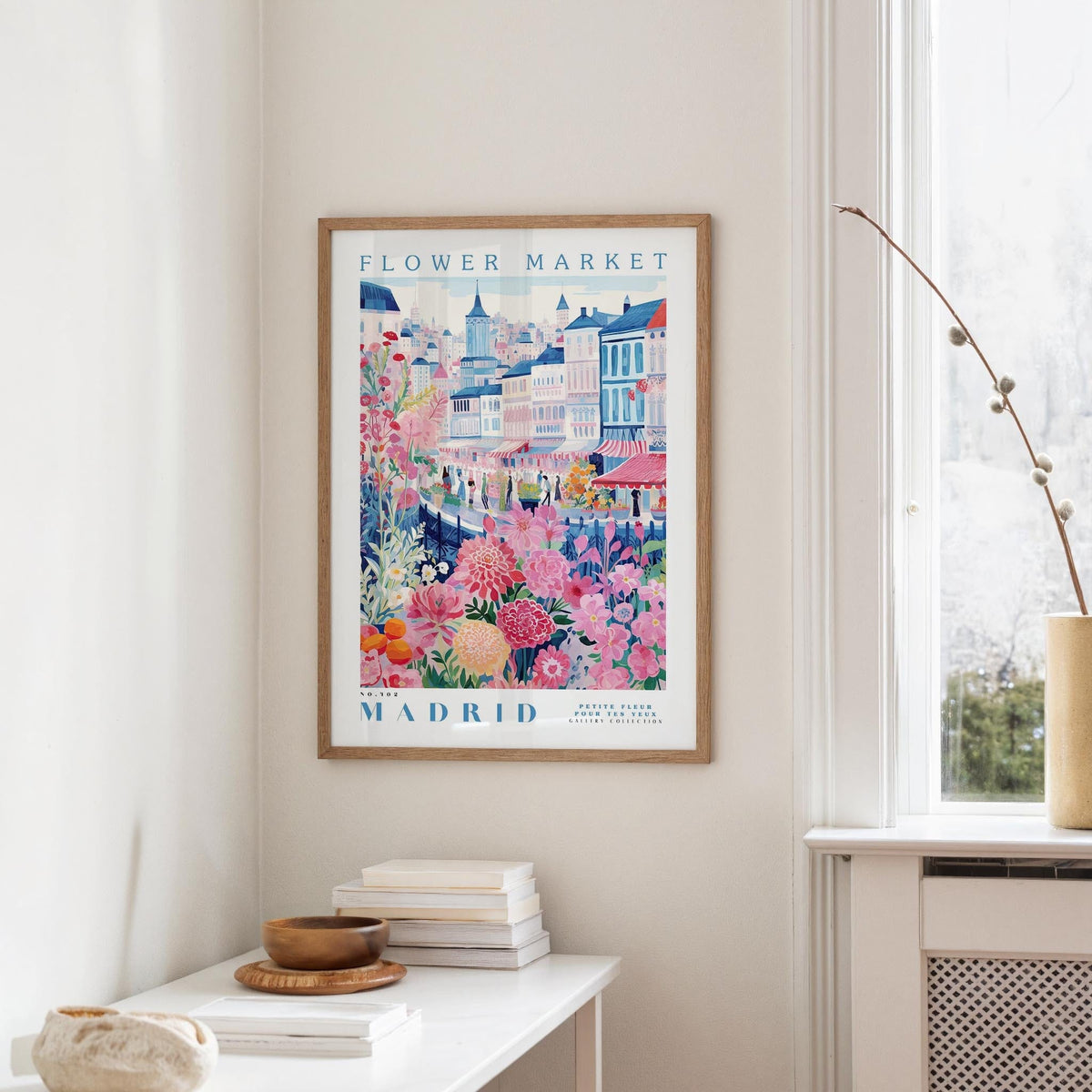 a framed poster of a colorful street scene in Madrid, Spain, hanging on a wall.