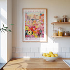 a kitchen counter with a bowl of lemons, a framed poster of a flower market, and shelves with jars and containers.