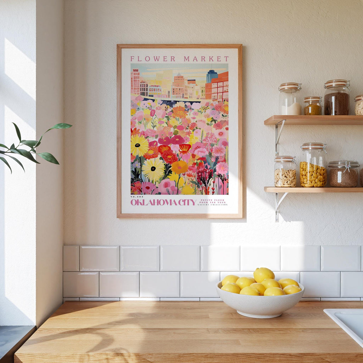 a kitchen counter with a bowl of lemons, a framed poster of a flower market, and shelves with jars and containers.