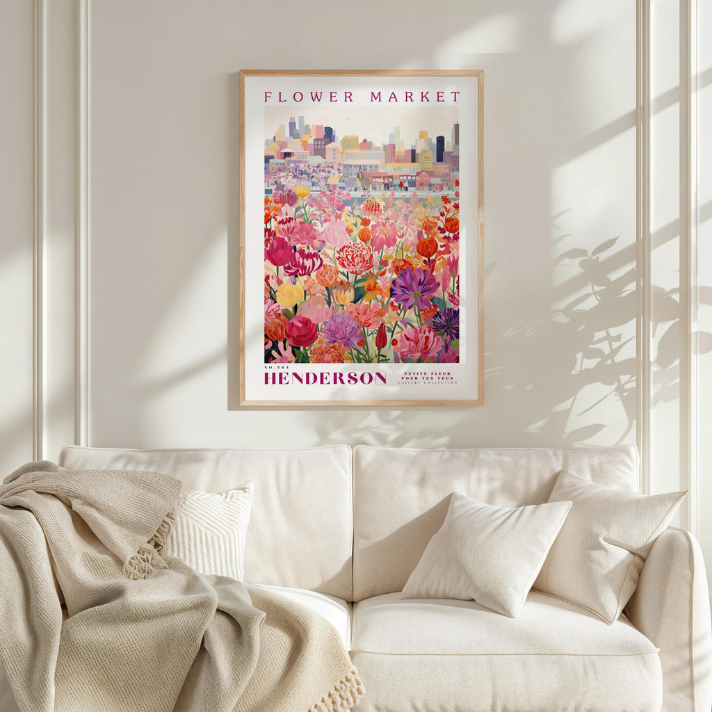 a framed poster of a colorful floral scene hanging on a wall above a white couch.