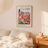 a bedroom setting with a framed poster of a colorful cityscape hanging on the wall above a bed with striped pillows.