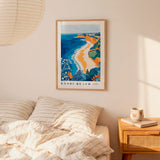 a bedroom scene with a framed poster of Bondi Beach hanging on the wall above a bed with striped pillows.