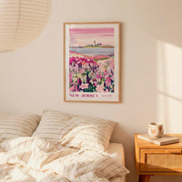a bedroom setting with a framed poster of a colorful landscape hanging on the wall above a bed with striped pillows.