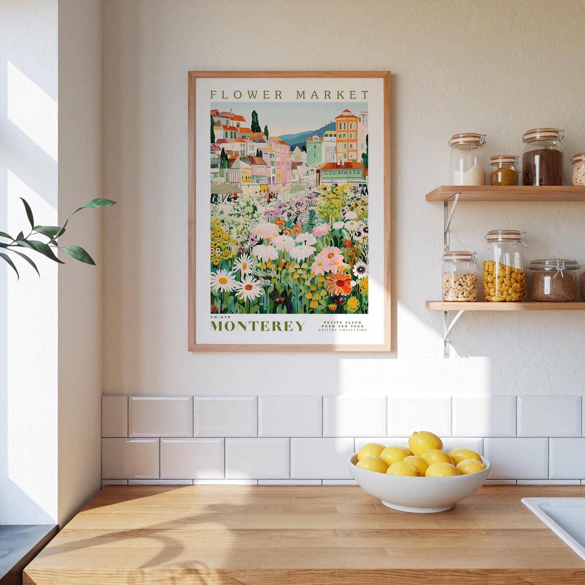 a framed poster of a flower market in Monterey, California, hanging on a wall above a kitchen counter with a bowl of lemons and jars of food on the counter.