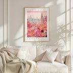 a framed poster of a cityscape with a pink and white color scheme, hanging on a wall above a white couch.