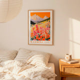 a bedroom scene with a framed poster of a mountain landscape hanging on the wall above a bed with striped pillows.