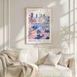a framed poster of a cityscape with a floral design, hanging on a wall above a white couch with pillows.