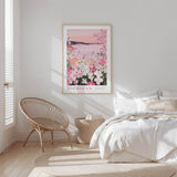 A bedroom with a large bed, a woven chair, and a framed poster of a floral scene hanging on the wall.