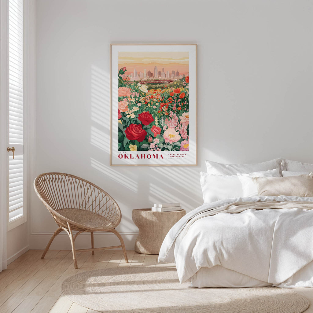a bedroom with a large framed poster of a garden hanging on the wall, a woven chair, and a bed with white bedding.