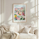 a poster of a flower market hanging on a wall above a white couch with a blanket draped over it.