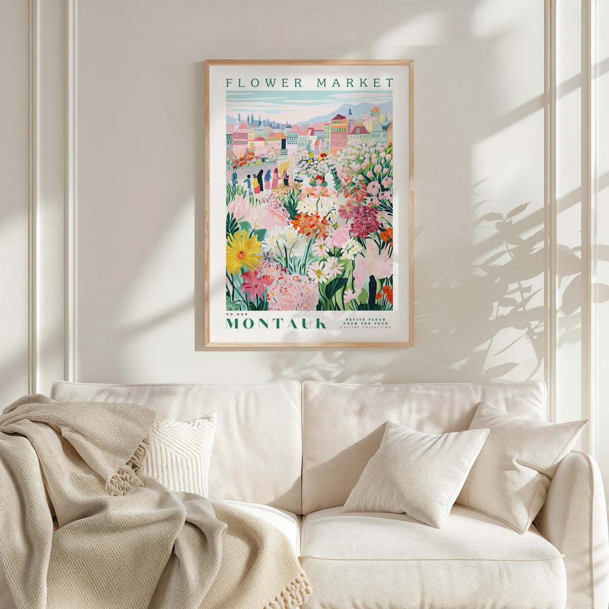 a poster of a flower market hanging on a wall above a white couch with a blanket draped over it.