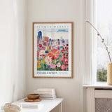 a framed poster of a colorful cityscape with flowers hanging on a wall in a room.