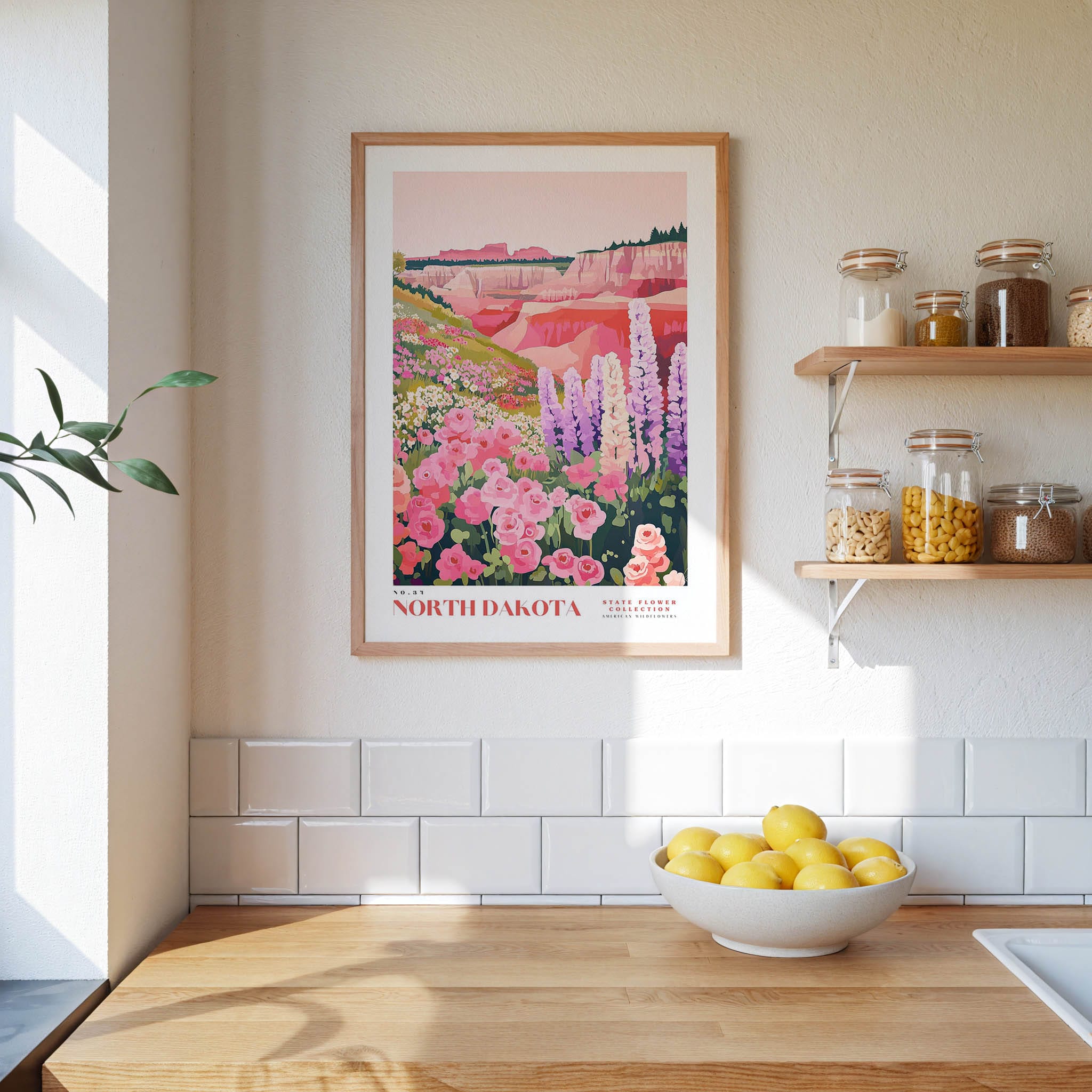 a kitchen scene with a framed poster of a colorful landscape of flowers hanging on the wall above a wooden countertop with a bowl of lemons.