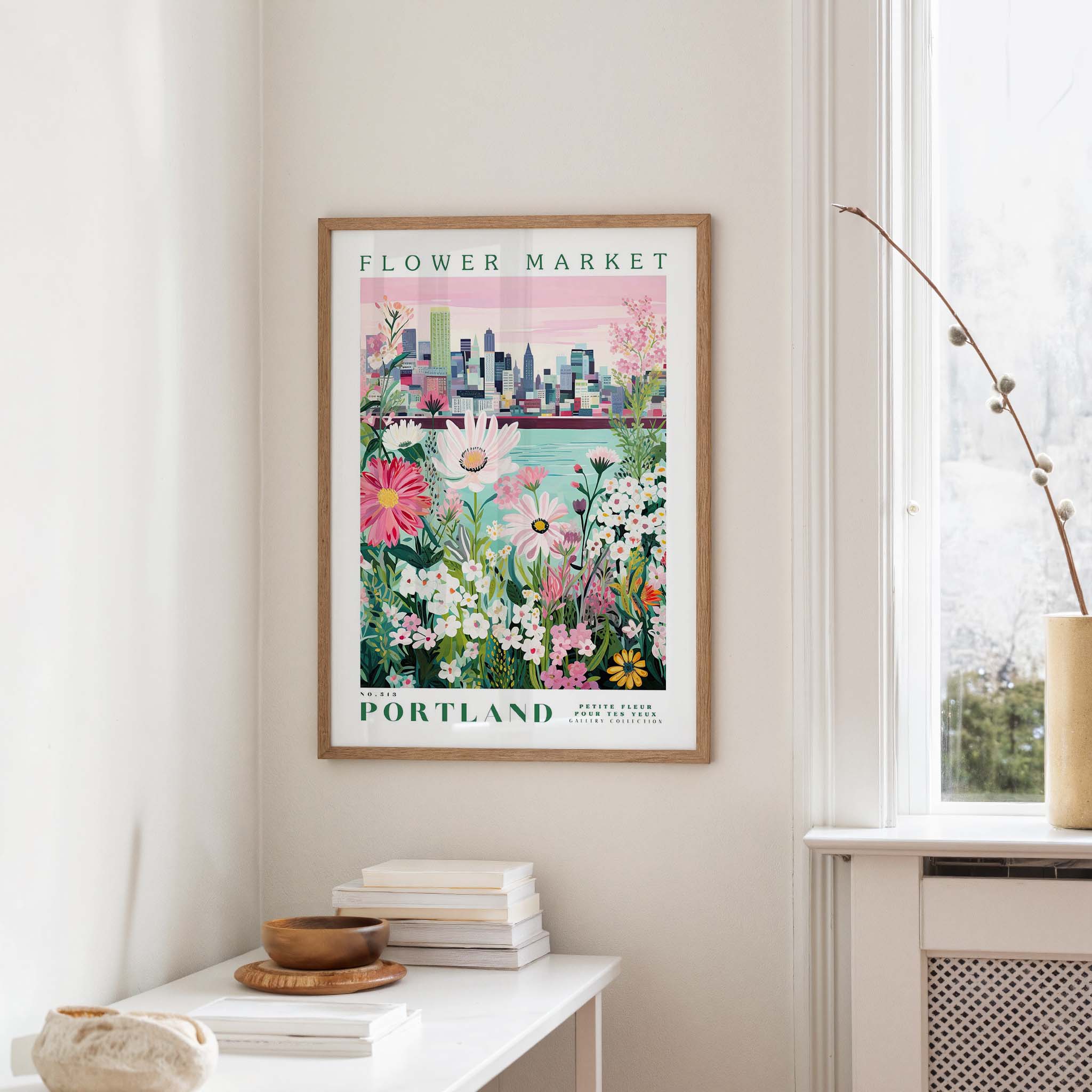 a framed poster of a cityscape with a flower market in Portland, Oregon, hanging on a wall.