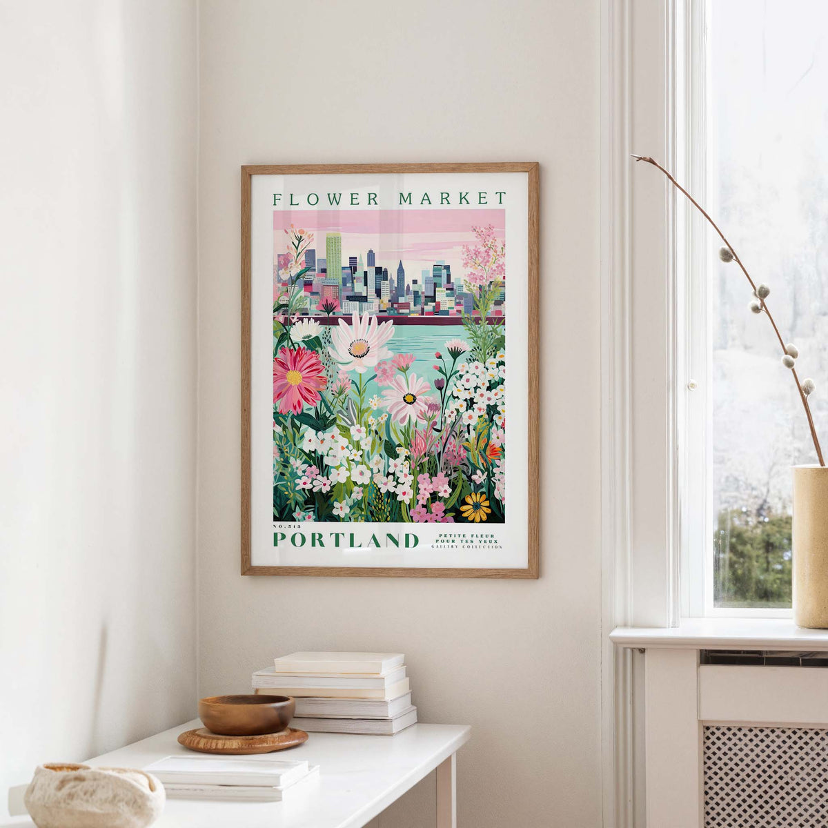 a framed poster of a cityscape with a flower market in Portland, Oregon, hanging on a wall.