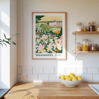 a framed poster of a flower garden hanging on a wall above a kitchen counter with a bowl of lemons on it.