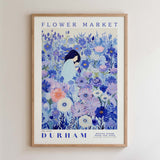 The image is a framed poster depicting a woman surrounded by a vibrant, colorful floral scene.