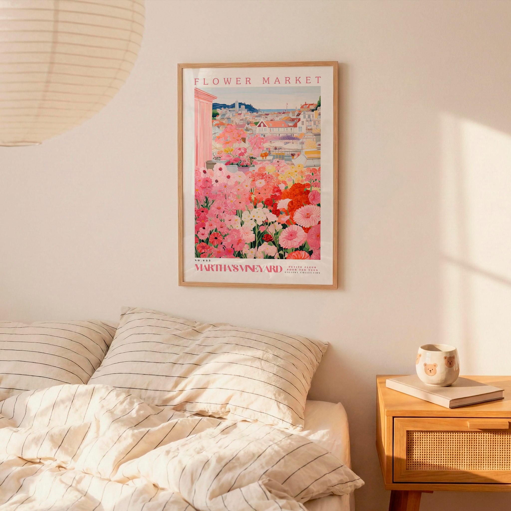 a bedroom scene with a framed poster of a flower market hanging on the wall above a bed with striped pillows.